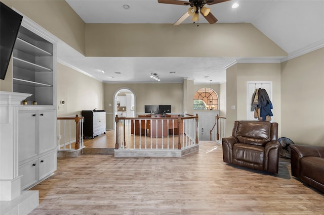 living area with arched walkways, a ceiling fan, light wood-style floors, vaulted ceiling, and ornamental molding