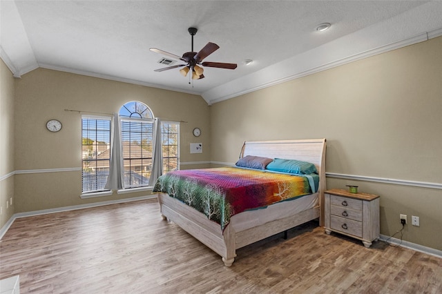 bedroom with lofted ceiling, crown molding, wood finished floors, and baseboards