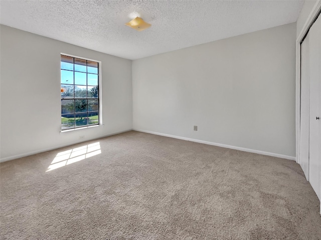 carpeted spare room with baseboards and a textured ceiling