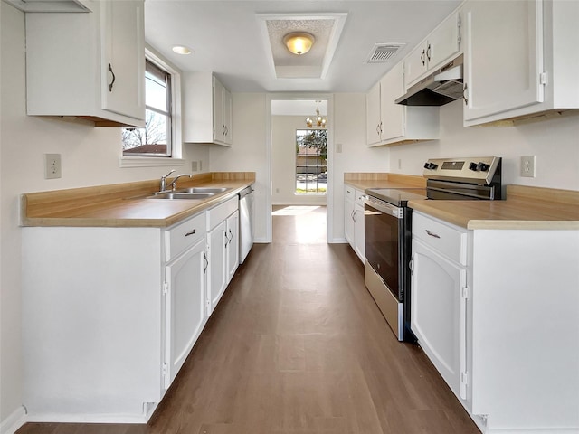 kitchen with under cabinet range hood, a sink, white cabinetry, visible vents, and appliances with stainless steel finishes