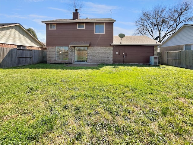 back of house featuring brick siding, a lawn, central AC unit, and a fenced backyard