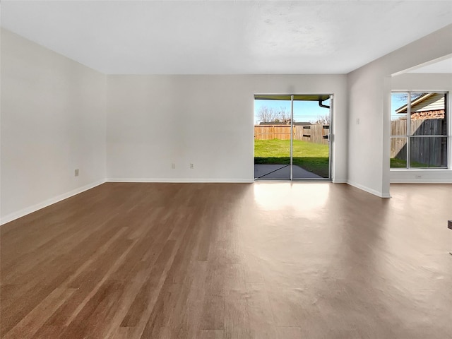 spare room with baseboards and wood finished floors