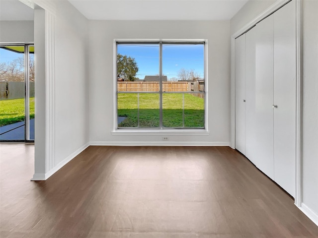 unfurnished bedroom with multiple windows, baseboards, and wood finished floors