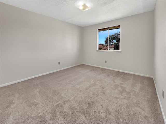 empty room featuring carpet floors, baseboards, and a textured ceiling