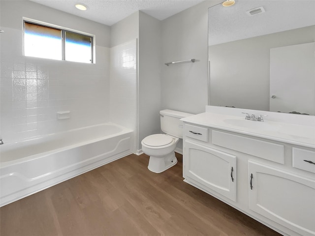 full bathroom featuring visible vents, toilet, wood finished floors, a textured ceiling, and vanity