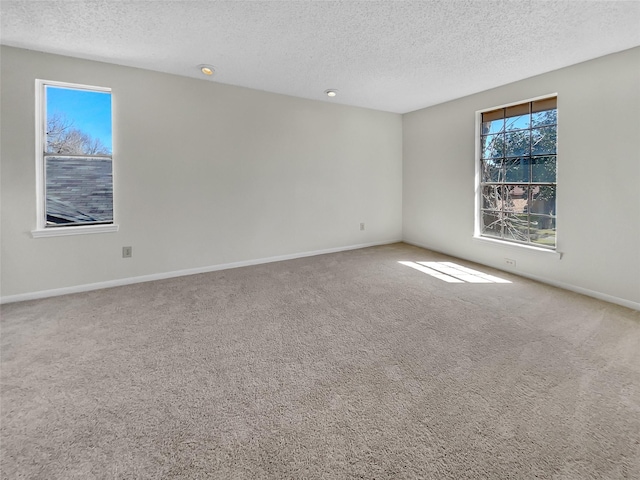 carpeted empty room featuring a textured ceiling and baseboards