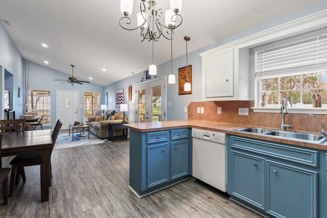 kitchen featuring blue cabinets, white dishwasher, a sink, and a peninsula