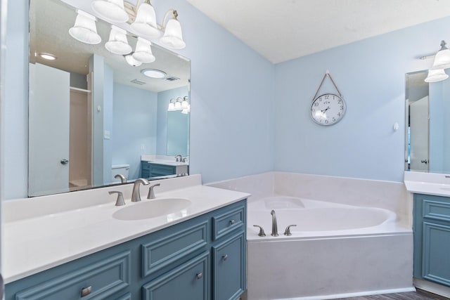 full bathroom with a garden tub, two vanities, toilet, a shower with shower door, and a sink