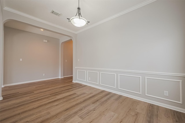 unfurnished room featuring light wood-style floors, visible vents, arched walkways, and crown molding