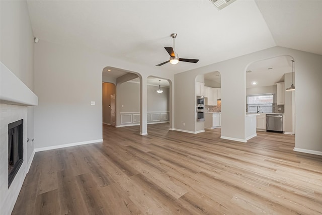 unfurnished living room featuring light wood-style floors, a fireplace, a sink, and visible vents