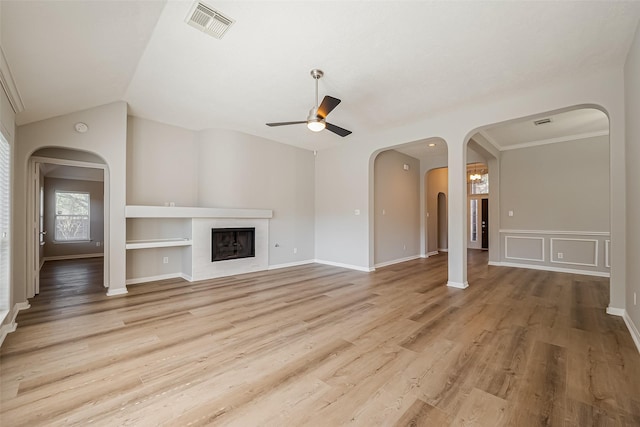 unfurnished living room with ceiling fan, lofted ceiling, a fireplace, wood finished floors, and visible vents