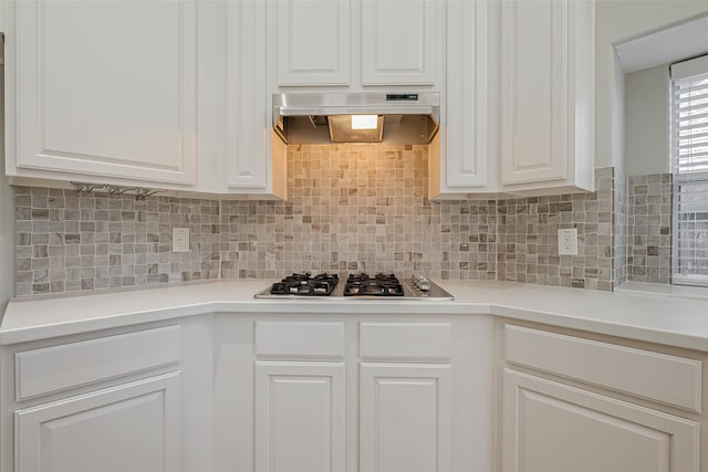 kitchen with stainless steel gas cooktop, backsplash, white cabinetry, and range hood