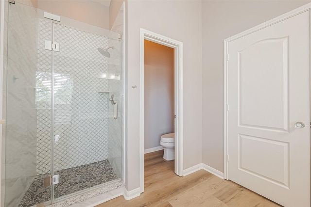 full bath featuring baseboards, wood finished floors, toilet, and a shower stall