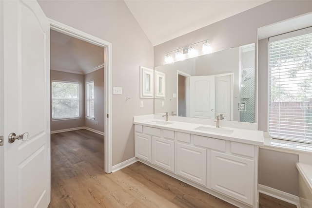 full bath featuring lofted ceiling, double vanity, wood finished floors, and a sink