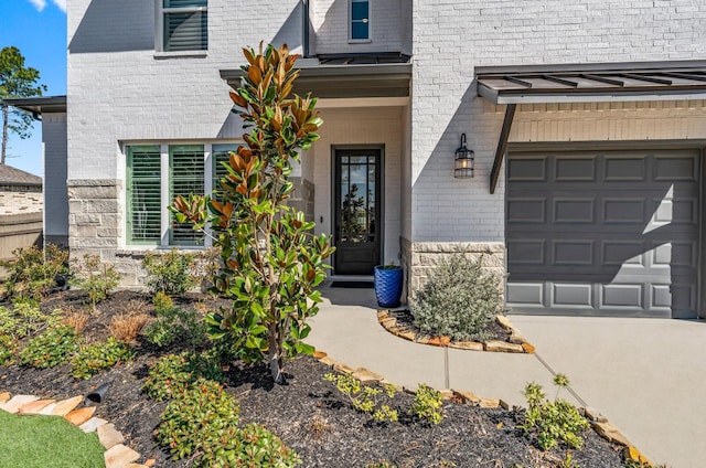 entrance to property featuring a garage, a standing seam roof, brick siding, and driveway