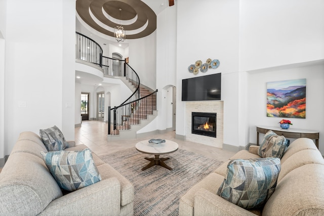 living room with baseboards, a tile fireplace, a towering ceiling, stairs, and a chandelier