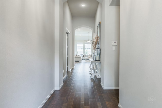 hall with baseboards, arched walkways, and wood finished floors