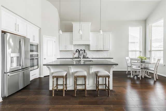 kitchen with dark countertops, dark wood-style floors, a kitchen bar, and appliances with stainless steel finishes