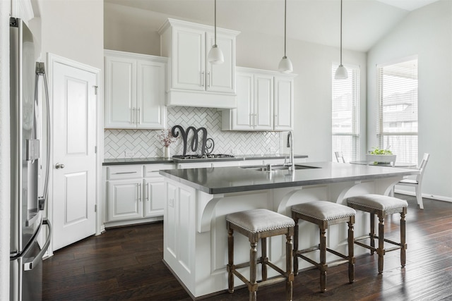 kitchen with dark wood-style flooring, a sink, white cabinets, vaulted ceiling, and appliances with stainless steel finishes