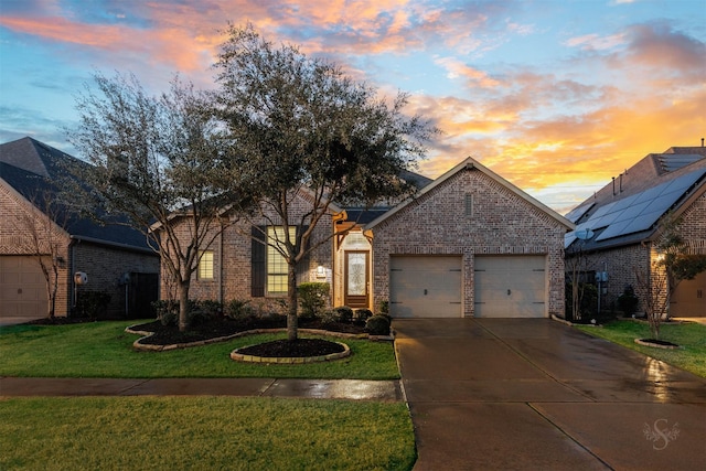 view of front of house featuring a garage, brick siding, driveway, and a lawn