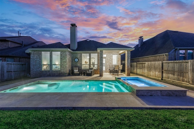 view of pool with a patio, a fenced backyard, and a pool with connected hot tub