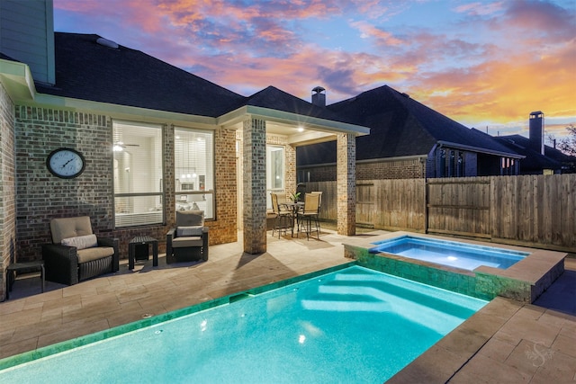 view of swimming pool with a pool with connected hot tub, fence, and a patio