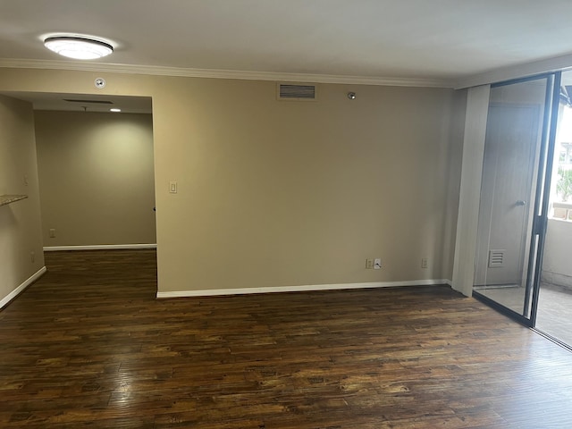 unfurnished room featuring dark wood-type flooring, visible vents, crown molding, and baseboards