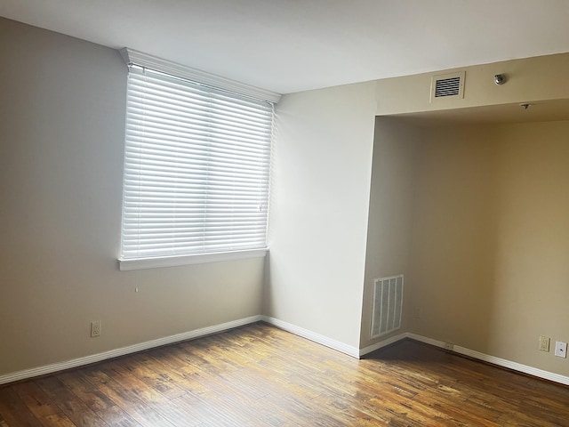 empty room with baseboards, wood finished floors, and visible vents