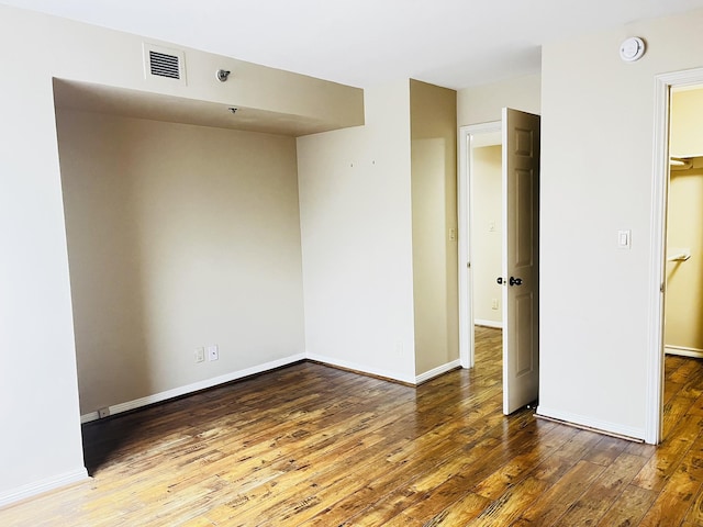 unfurnished room featuring hardwood / wood-style floors, baseboards, and visible vents
