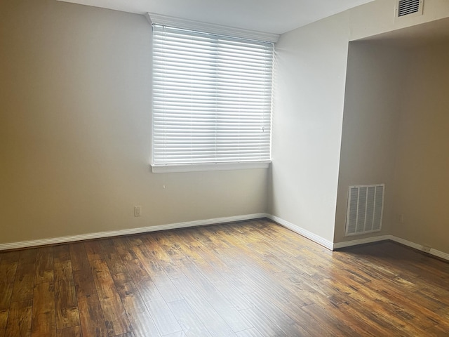 spare room with dark wood finished floors, baseboards, and visible vents