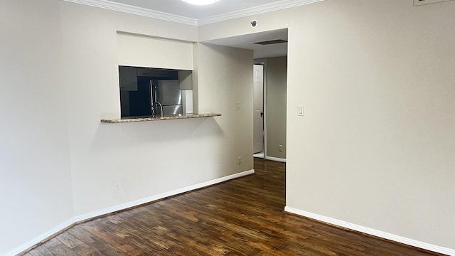 unfurnished room featuring wood finished floors, visible vents, baseboards, and ornamental molding