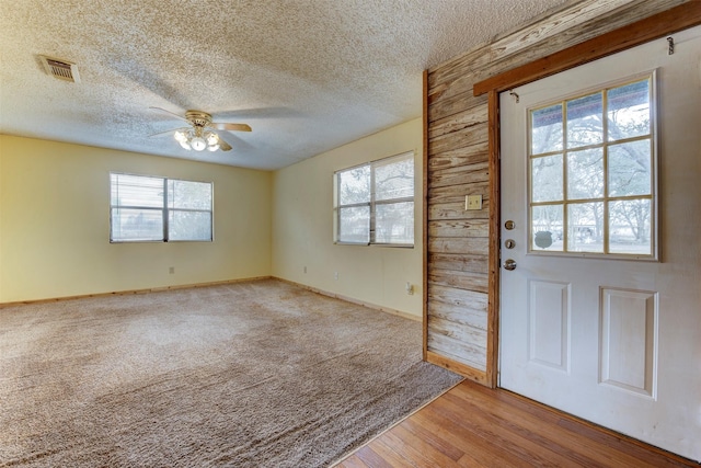 foyer entrance with visible vents, light wood-style flooring, a ceiling fan, a textured ceiling, and baseboards