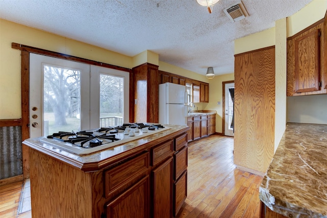 kitchen with white appliances, visible vents, light wood-style flooring, light countertops, and a textured ceiling