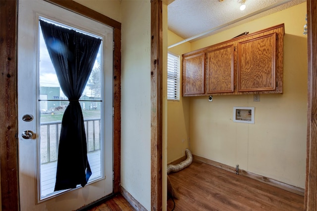 doorway featuring dark wood-style floors, a textured ceiling, baseboards, and a wealth of natural light