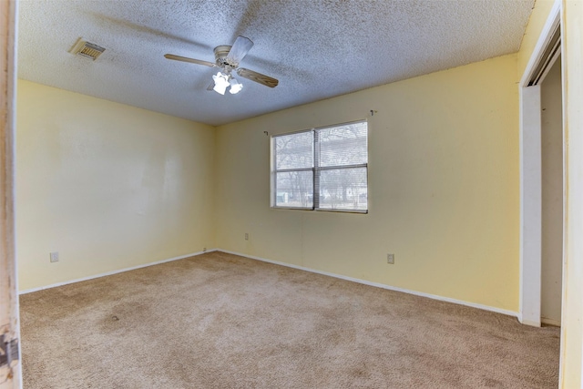 empty room with a textured ceiling, carpet floors, visible vents, and a ceiling fan