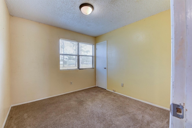 empty room with carpet floors, baseboards, and a textured ceiling