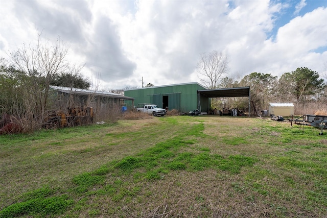 view of yard featuring an outdoor structure, a carport, and an outbuilding