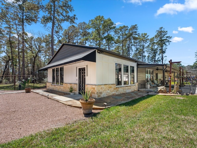 exterior space with board and batten siding, fence, a yard, a patio area, and stone siding