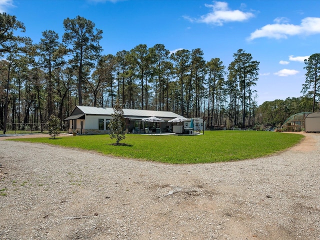 view of front of house with metal roof, driveway, and a front lawn