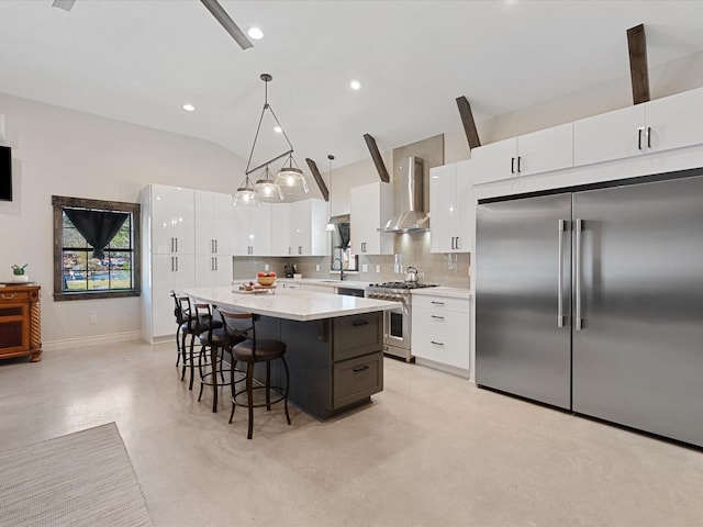 kitchen featuring a breakfast bar, vaulted ceiling, wall chimney range hood, premium appliances, and backsplash