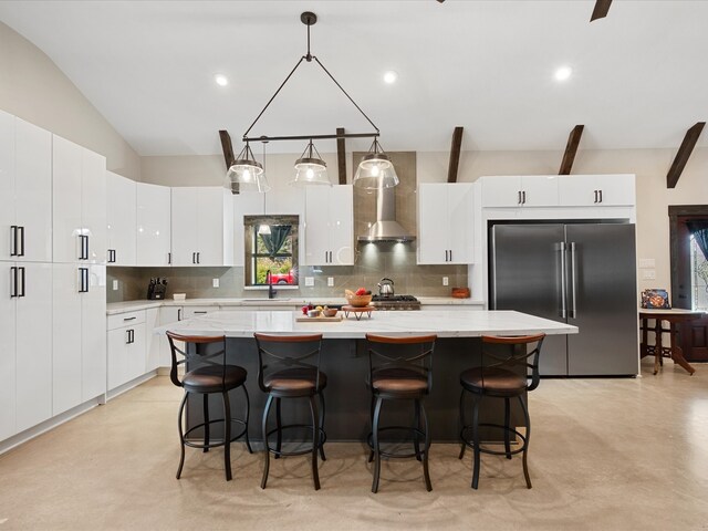 kitchen with backsplash, high end fridge, wall chimney exhaust hood, and a sink