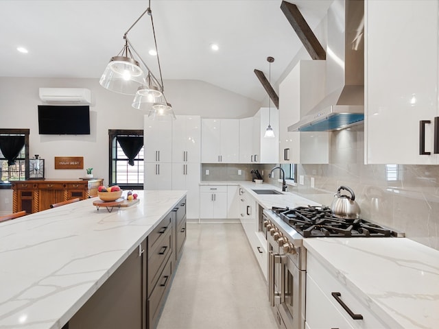 kitchen with lofted ceiling, a sink, an AC wall unit, high end stainless steel range, and wall chimney range hood