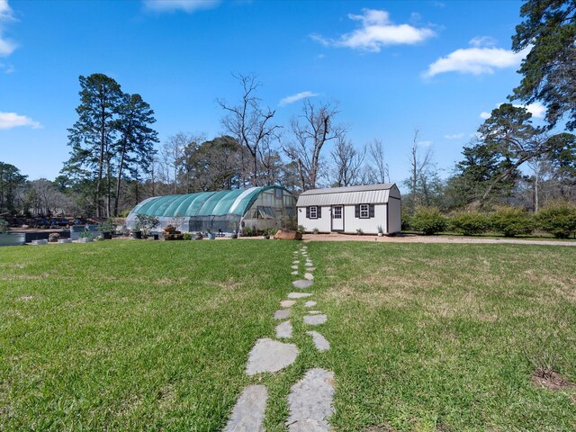 exterior space with an outbuilding, a greenhouse, and a front yard