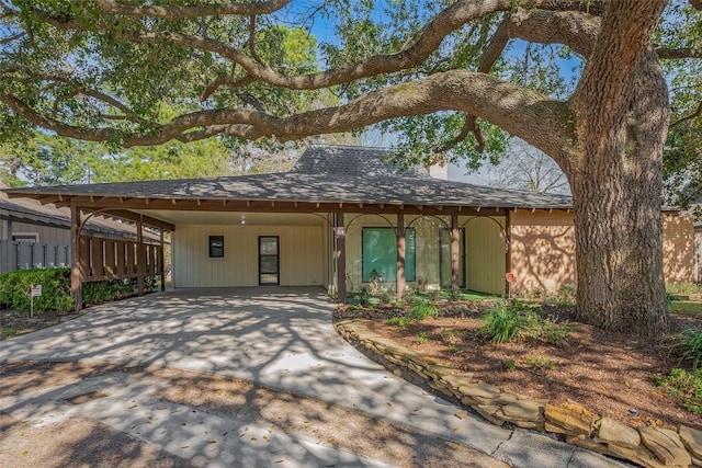 view of front of home featuring a carport, roof with shingles, and driveway