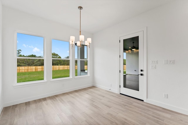 unfurnished dining area with an inviting chandelier, baseboards, and wood finished floors