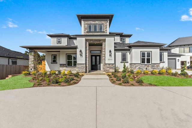 view of front of house featuring a garage, stone siding, fence, and stucco siding