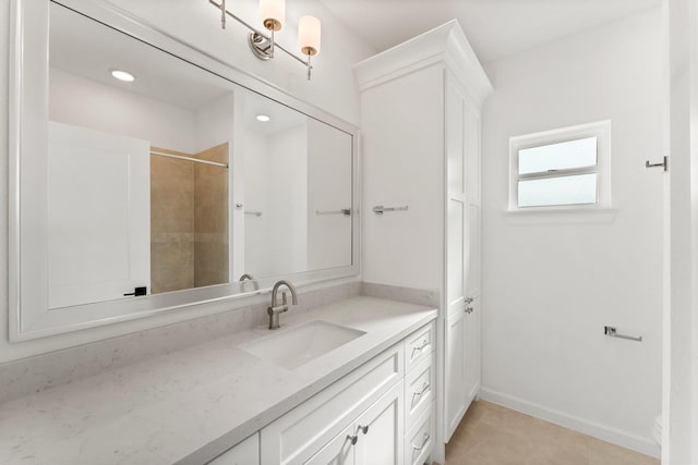 bathroom with a shower, vanity, and baseboards