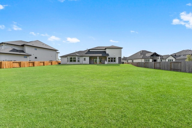 rear view of house featuring a yard and fence