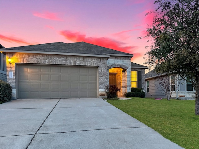 french provincial home with a garage, a shingled roof, concrete driveway, stone siding, and a yard