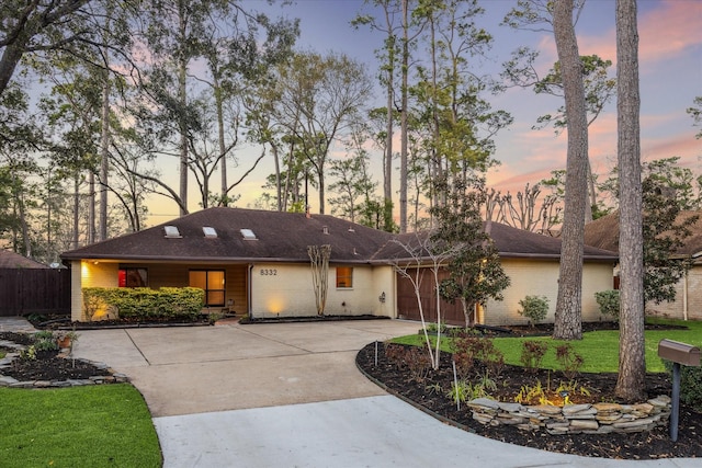 view of front of property featuring concrete driveway, an attached garage, fence, a yard, and brick siding